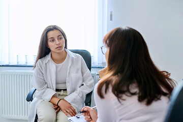School counselor psychologist talking to teenage student girl