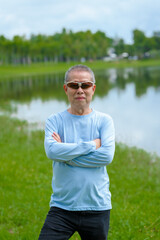 Happiness in nature, elderly asian man in blue shirt blissful time in the park, nature's comfort, parkside relaxation, peaceful moments, refreshing break