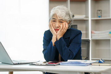 Mature businesswoman at her desk, overwhelmed by stress, feeling the weight of failure, and suffering from a headache, Stressful workday, Overwhelmed at work, Corporate crisis