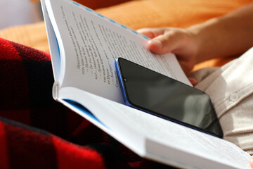 the child hides the phone in the book. the problem of children dependence on mobile devices.