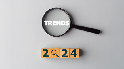 2024 trends concept. Magnifying glass and wooden cubes with the word Trends. Banner of business trend inspiration and ideas for new year direction.