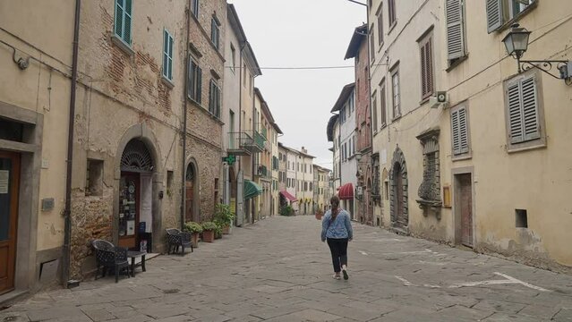 Woman Walking On Typical Street In The Town Of Lucignano In Arezzo, Italy. wide