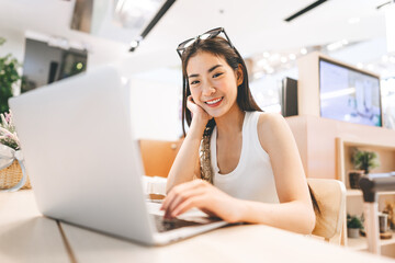 Young asian woman sitting indoors cafe using laptop influencer gen z modern lifestyles