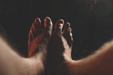 male feet in the dark. Close-up of man's bare feet