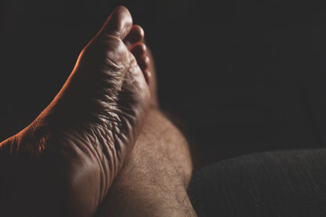 male feet in the dark. Close-up of man's bare feet