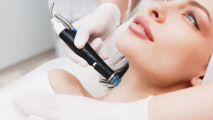 Professional dermatologist in medical gloves doing hydro peeling procedure for beautiful woman patient in cosmetology clinic. Close up facial treatment.