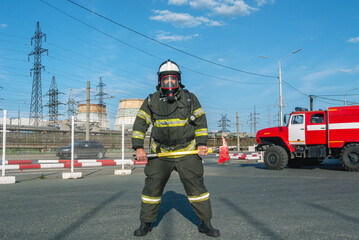 A firefighter in protective clothing and helmet holds an assault axe in his hands. A firefighter on...