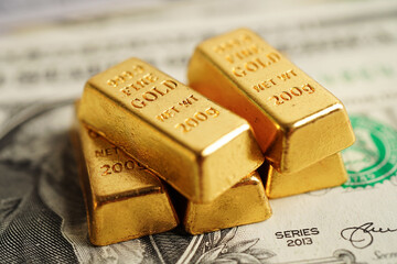 Gold bars on US dollar banknote money, finance trading investment business currency concept.