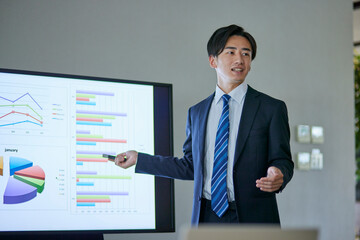 会議室にてプレゼンテーションを行う若い日本人ビジネスマン