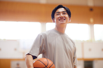 体育館でバスケットボールの練習をする日本人大学生の男性