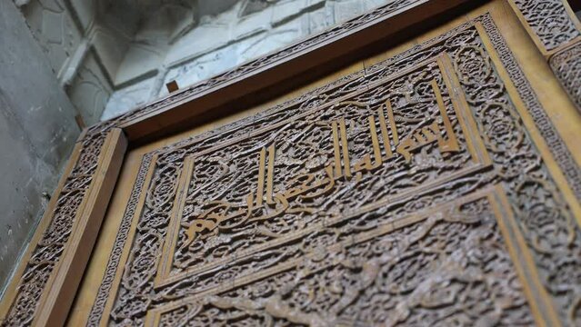 wall made of wood with carved patterns and inscriptions - In the name of God, the most gracious, the most merciful