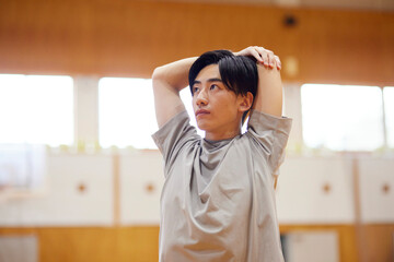 体育館でストレッチを行う日本人大学生の男性