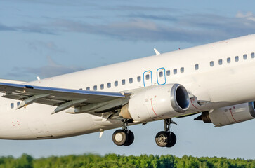 Airliner jet white plane take off in the air on tree background