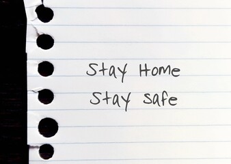 Torn ripped lined note paper with hand written text STAY HOME STAY SAFE - concept of self motvation...