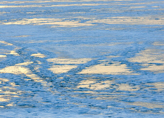 Snow on the lake in winter in the rays of sunset.