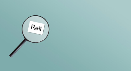 REIT text concept. Magnifier glass text with notebook and pen