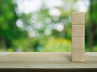 Four wood block cubes on wooden table over blur green tree in park