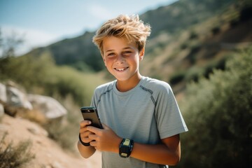 Portrait of smiling boy using mobile phone while standing on mountain trail - obrazy, fototapety, plakaty