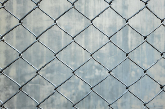 Rust proof galvanized steel mesh fence against concrete wall background.