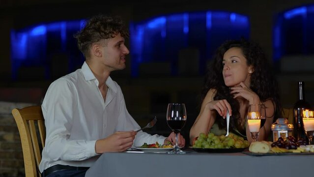 Happy young man feeding his girlfriend while having the date outdoor in the evening. Romantic date on the roof. Romantic concept. Couple in love. Real time