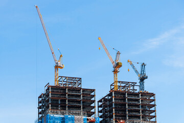 Building construction site and cranes with a blue sky background.