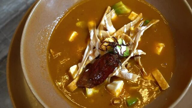 caldo de tortilla, rich tortilla soup Mexican dish with great flavor, vegetable broth with meat, crispy tortilla strips, avocado and chipotle chili, delicious dish.