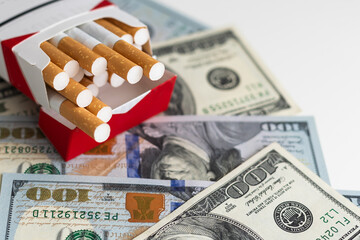 white cigarettes lying on the dollar bills. concept of financial cost of smoking.