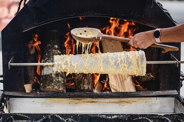 Initial stage of preparation of a tree cake, Lithuanian šakotis, Polish sękacz, Belarusian bankucha, German baumkuchen made of butter, egg whites and yolks, flour, sugar, cooked over an open fire