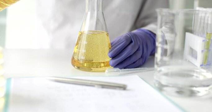 Chemist pours edible oil and petroleum products into flask in lab. Control of oil quality indicators