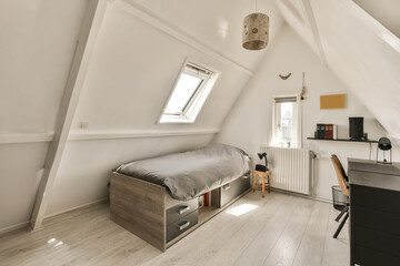 a bedroom with white walls and wood flooring, including a bed in the corner of the room on the left is a desk