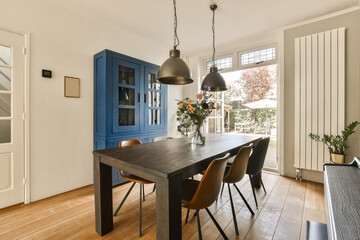 a dining room with wooden flooring and blue cabinetd cupboards on the wall, next to a window