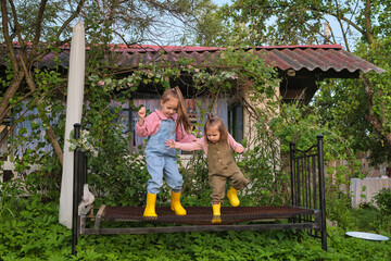 Obraz premium Hidden behind a house, an overgrown garden becomes the stage for countless stories and adventures, as these girls demonstrate. Magic Hidden in Our Backyards.