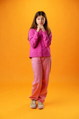 Thinking teen girl in studio over yellow background