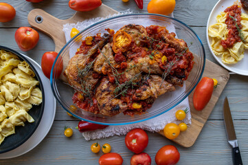 Roasted chicken parts with fresh garden tomatoes, garlic, onions and herbs in a casserole
