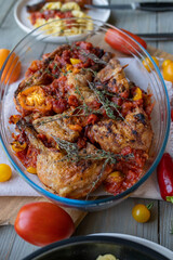 Roasted chicken legs with italian braised tomatoes and herbs in a casserole dish