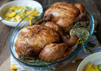 Roast whole chicken in glass casserole with salad on wooden table