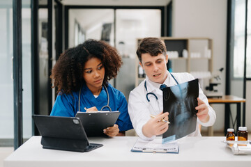  Doctor Talks With Professional Head Nurse or Surgeon, They Use Digital tablet Computer. Diverse Team of Health Care Specialists Discussing Test Result on desk in hospital .