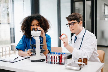 Focused mature male doctor and African female nurse look at tablet and laptop discuss anamnesis together. Concentrated diverse medical professionals in hospital.