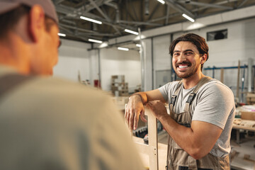 Two young men carpenters making furniture in warehouse of wood factory