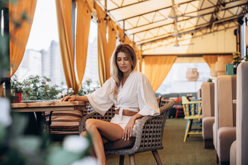Fototapeta premium Beautiful blonde model woman, fashionable in a white suit, posing in a summer cafe