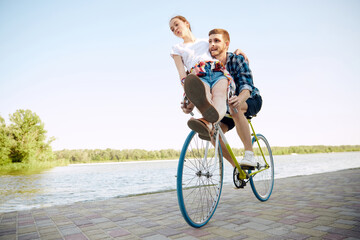 Bottom view portrait of young couple, woman and her boyfriend enjoying for bike ride in river enbankment on summer day. Romantic date concept.