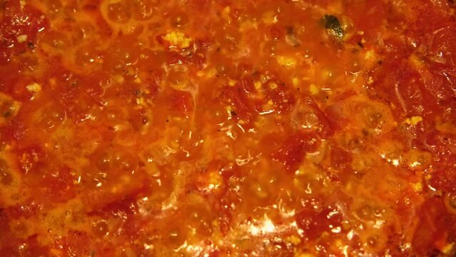 Preparation of Tomato sauce boiling in a pan on the kitchen. Classic home Hot tomato sauce cooking for pizza or pasta. Italian cuisine, food and drink footage. Homemade Sauteed Cooked Chopped Tomatoes