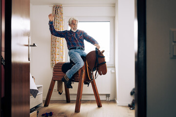 Senior Man Playing Cowboy With Toy Horse