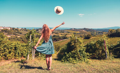 Fototapeta premium Happy woman tourist with blue dress and hat enjoying vineyards and winery in a valley- Chianty, Tuscany in Italy