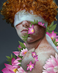 Blind love. Curly, redhead guy with covered eyes and blooming pink flowers around body. Freckled man. Contemporary art collage. Concept of floral aesthetics, natural beauty, inspiration, abstract art