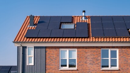 Fototapeta premium solar panels attached on the roof against a sunny sky Close up of new building with black solar panels. Zonnepanelen, Zonne energie, Translation: Solar panel, , Sun Energy