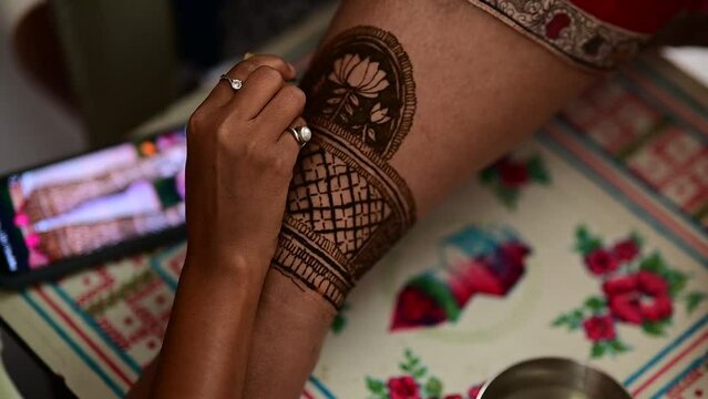 Applying Henna Tattoo on legs of Indian bride. Wedding Henna legs art. Henna Ceremony.