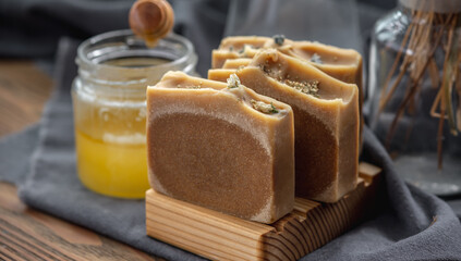 Pieces of natural honey soap handmade on a wooden soap dish. Beautiful atmospheric postcard