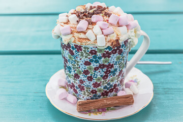 Hot chocolate with cream and marshmallows on turqoise wooden table