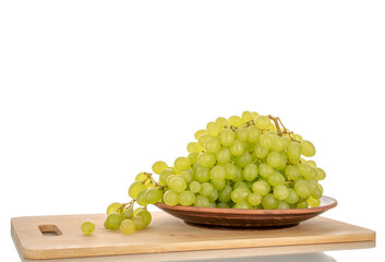Sweet organic grapes with clay plate on bamboo kitchen board, macro isolated on white background.